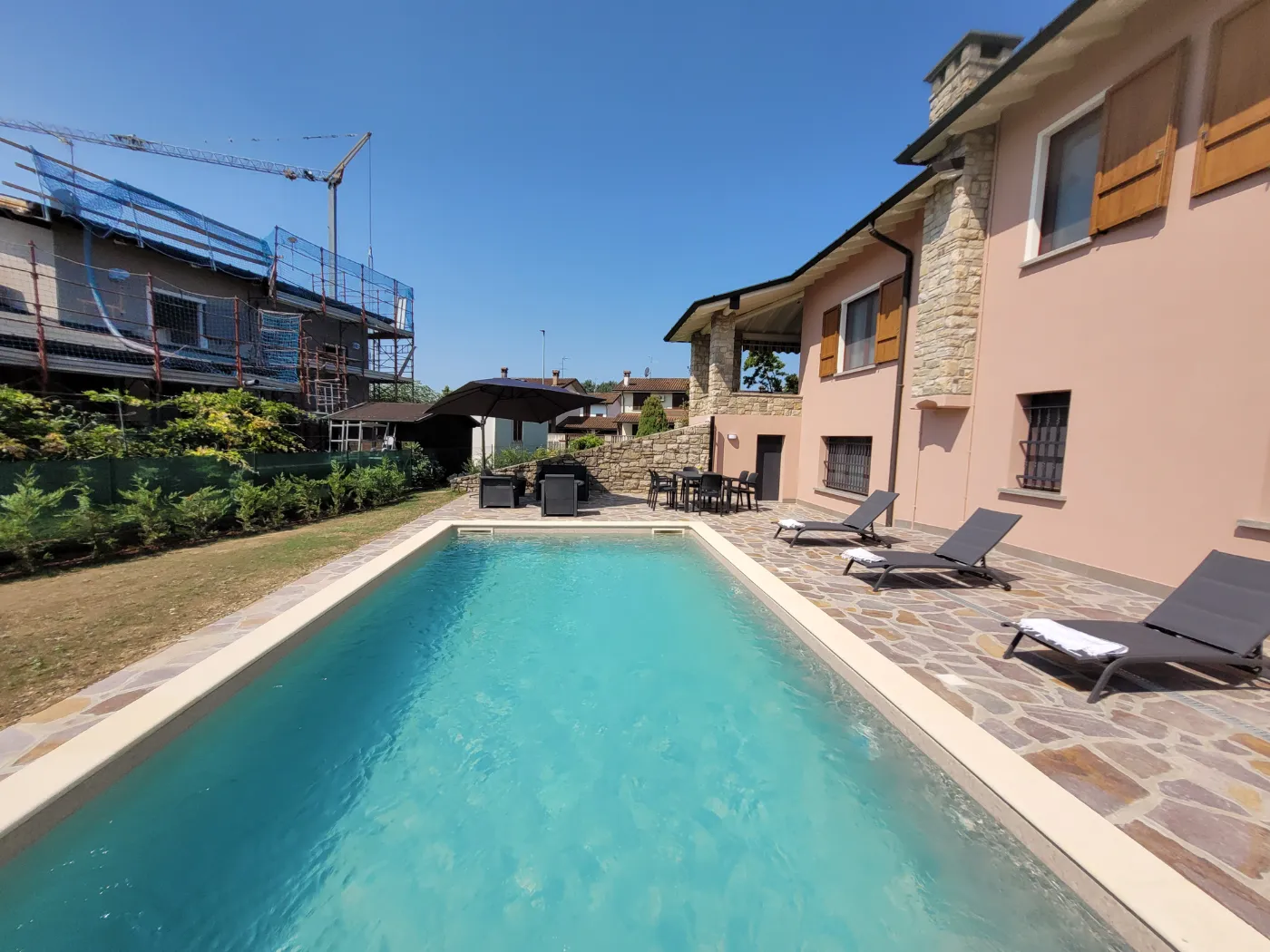 Piscina luxury villa con zona solarium e pavimentazioni design a Cremona